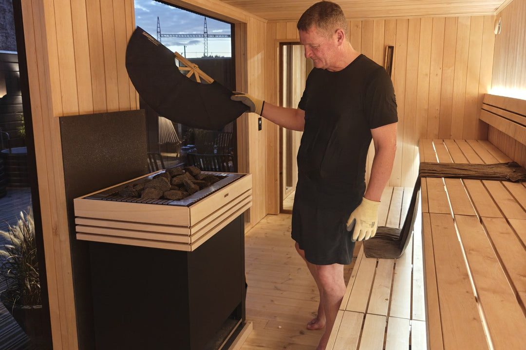 Gusmester Torben Mikkelsen laver gus ved saunaovnen i en sort uld-T-shirt